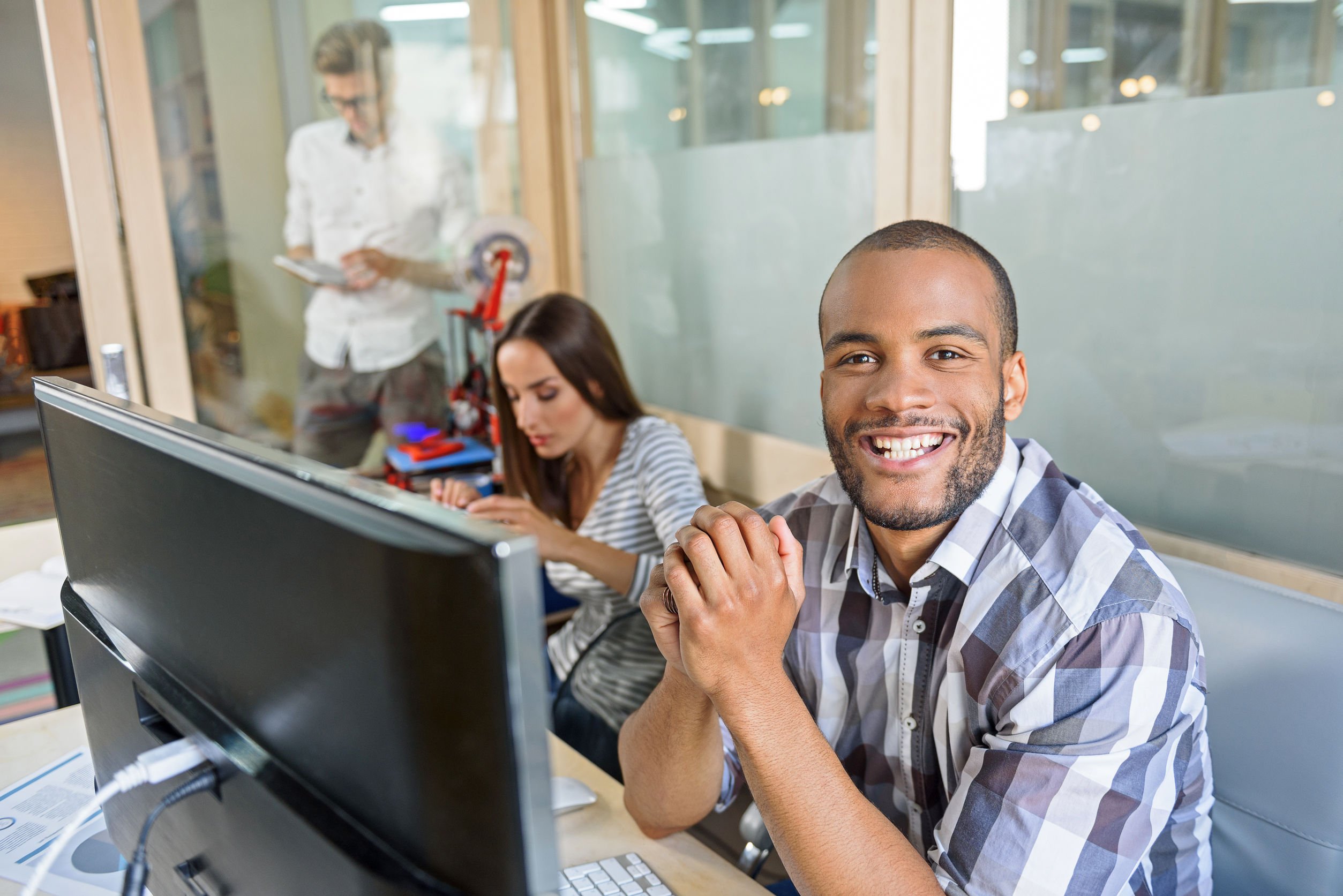 62647819-3d-printing-process-happy-young-man-is-sitting-near-computer-and-smiling-his-colleagues-are-working_62647819_m