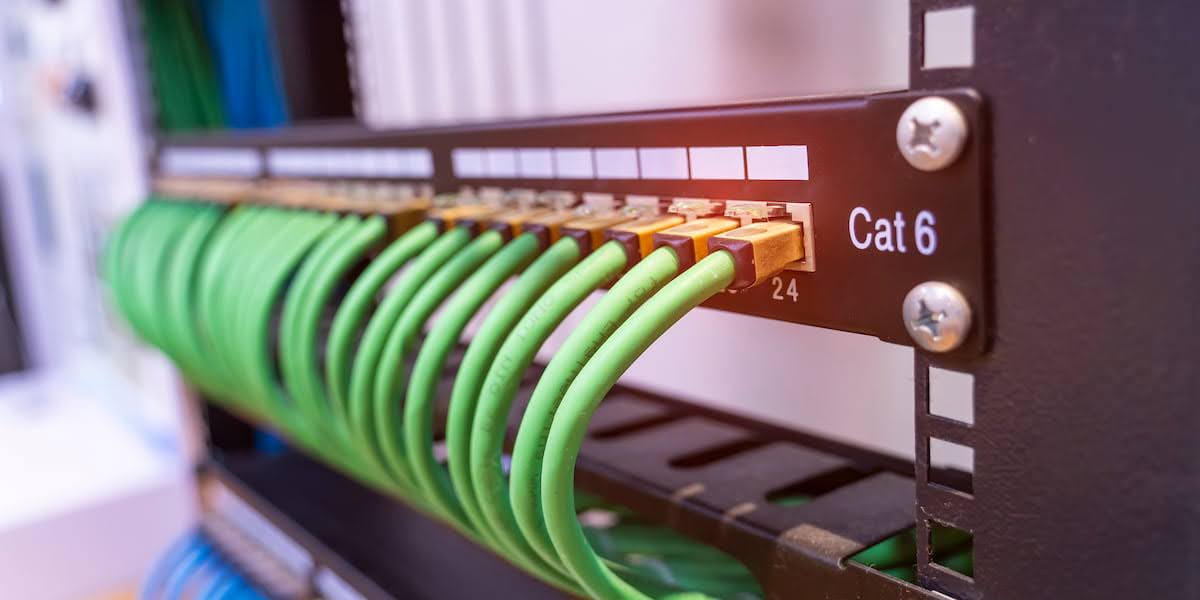 Close-up of a patch panel with green Ethernet cables connected, showing a cat 6 wiring diagram in a professional network setup.