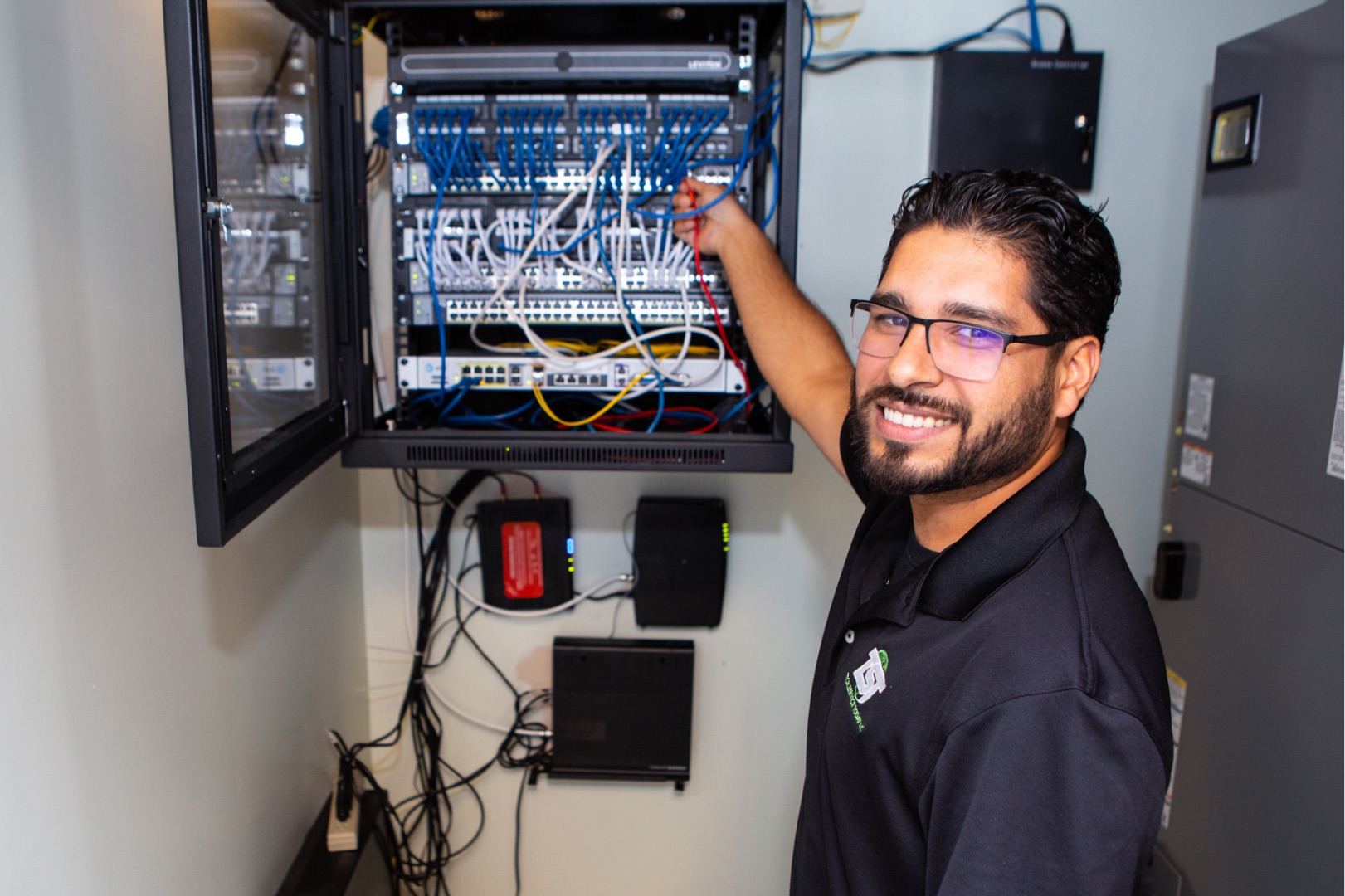 IT technician smiling while plugging in a wire.